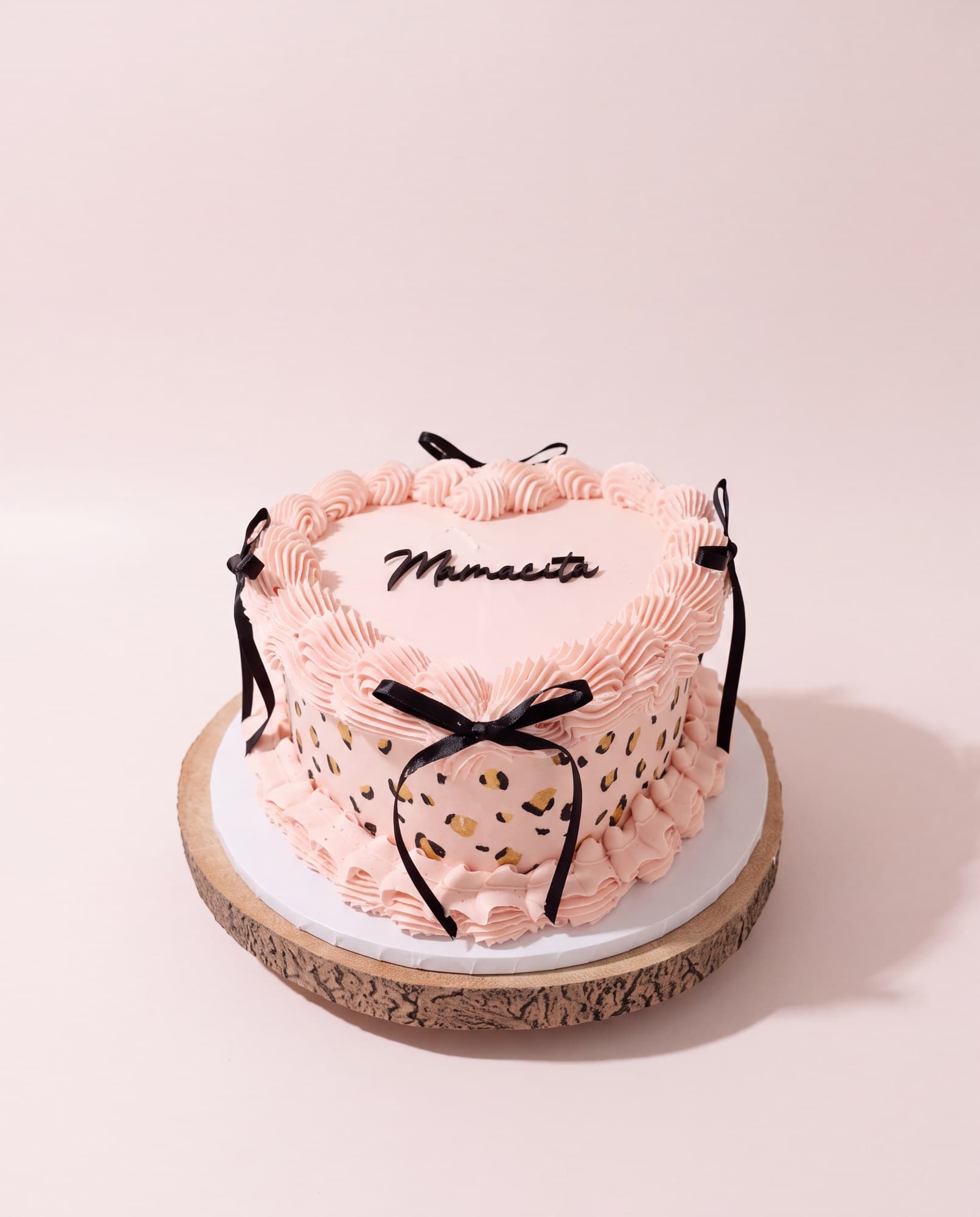 Pink heart cake with piped shells and black ribbon bows